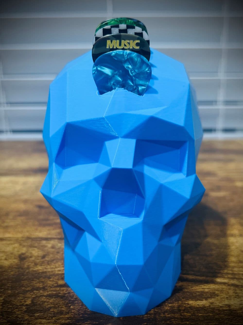 Porta-palhetas Caveira Rock vista frontal mostrando geometria low-poly e palhetas em leque