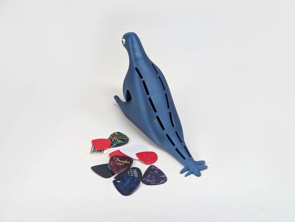 Detalhe do Porta-palhetas Dinossauro com múltiplas palhetas organizadas no dorso