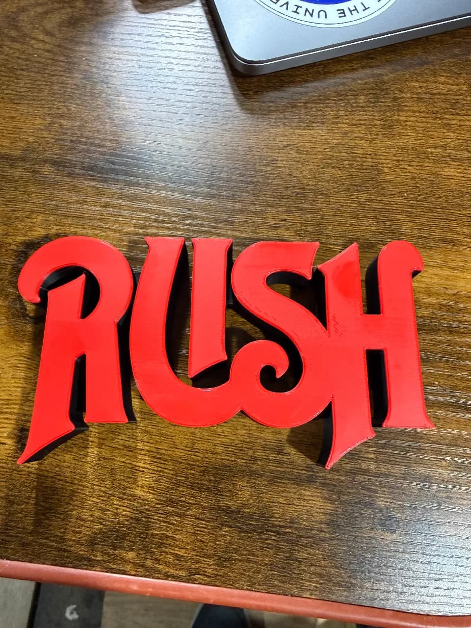 Escultura de logotipo em vermelho sobre mesa de madeira