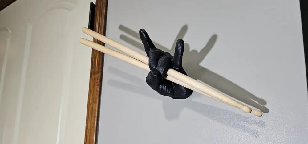 Porta-baquetas artesanal Mão do Rock na parede branca com baquetas