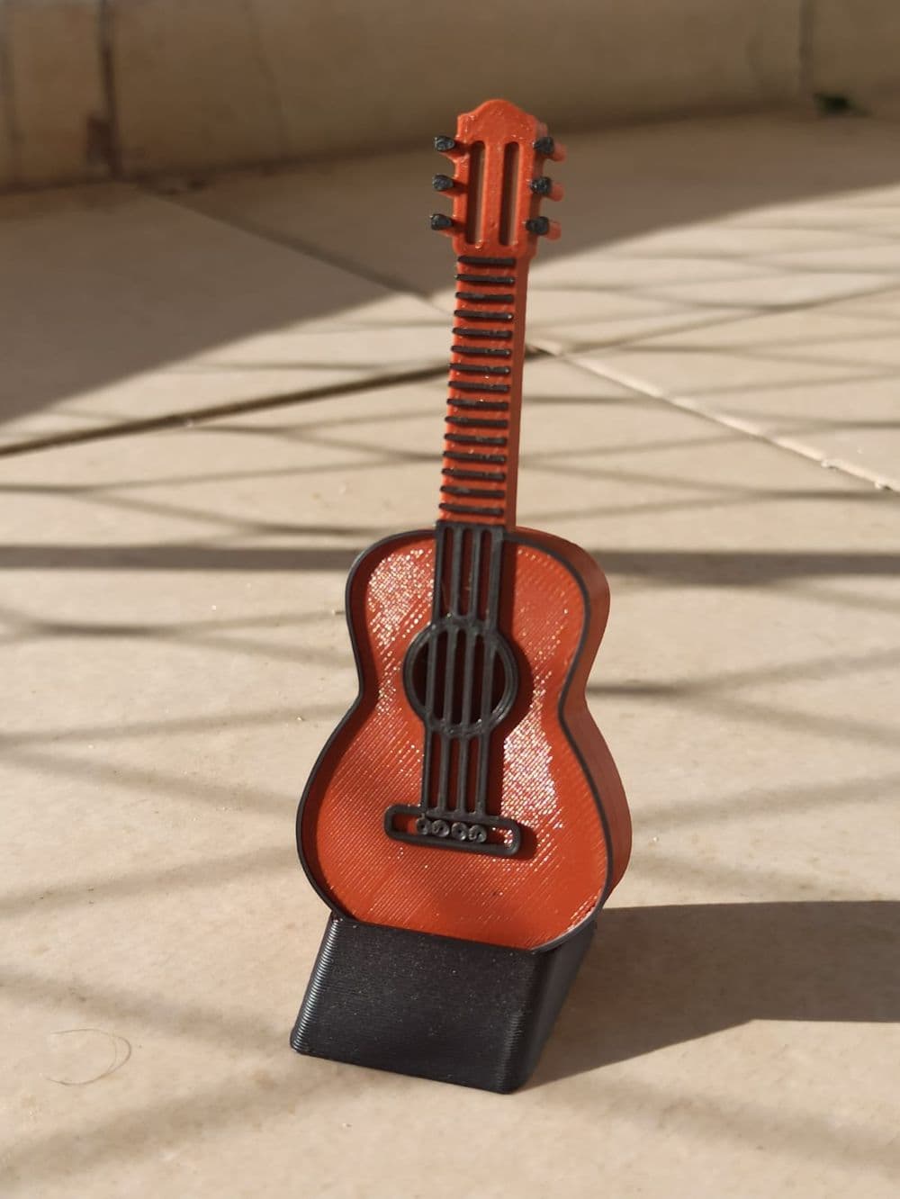 Porta-palheta guitarra com ímã em pé sobre a base preta, vista frontal