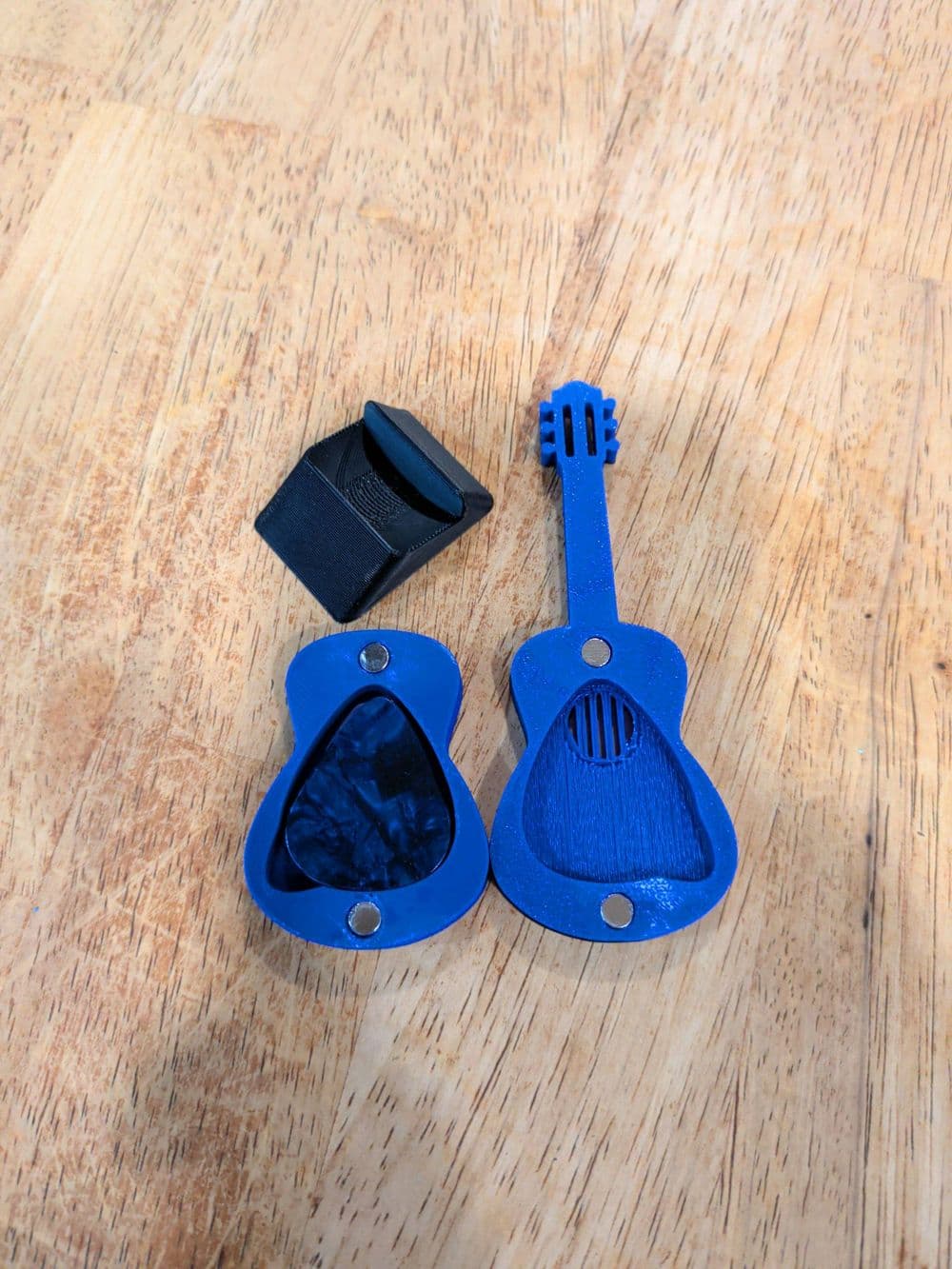 Porta-palheta guitarra com ímã sendo segurado na mão, mostrando o encaixe magnético